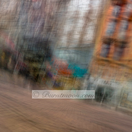 Blurred cityscape of Amsterdam featuring distorted buildings and storefronts, captured using Intentional Camera Movement (ICM) for an abstract and artistic effect.