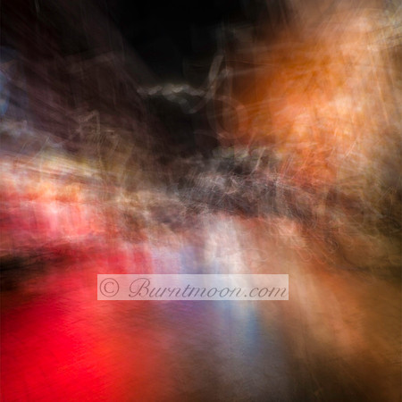 Abstract street scene in Amsterdam with blurred red, blue, and orange lights reflecting on wet pavement, created using intentional camera movement.